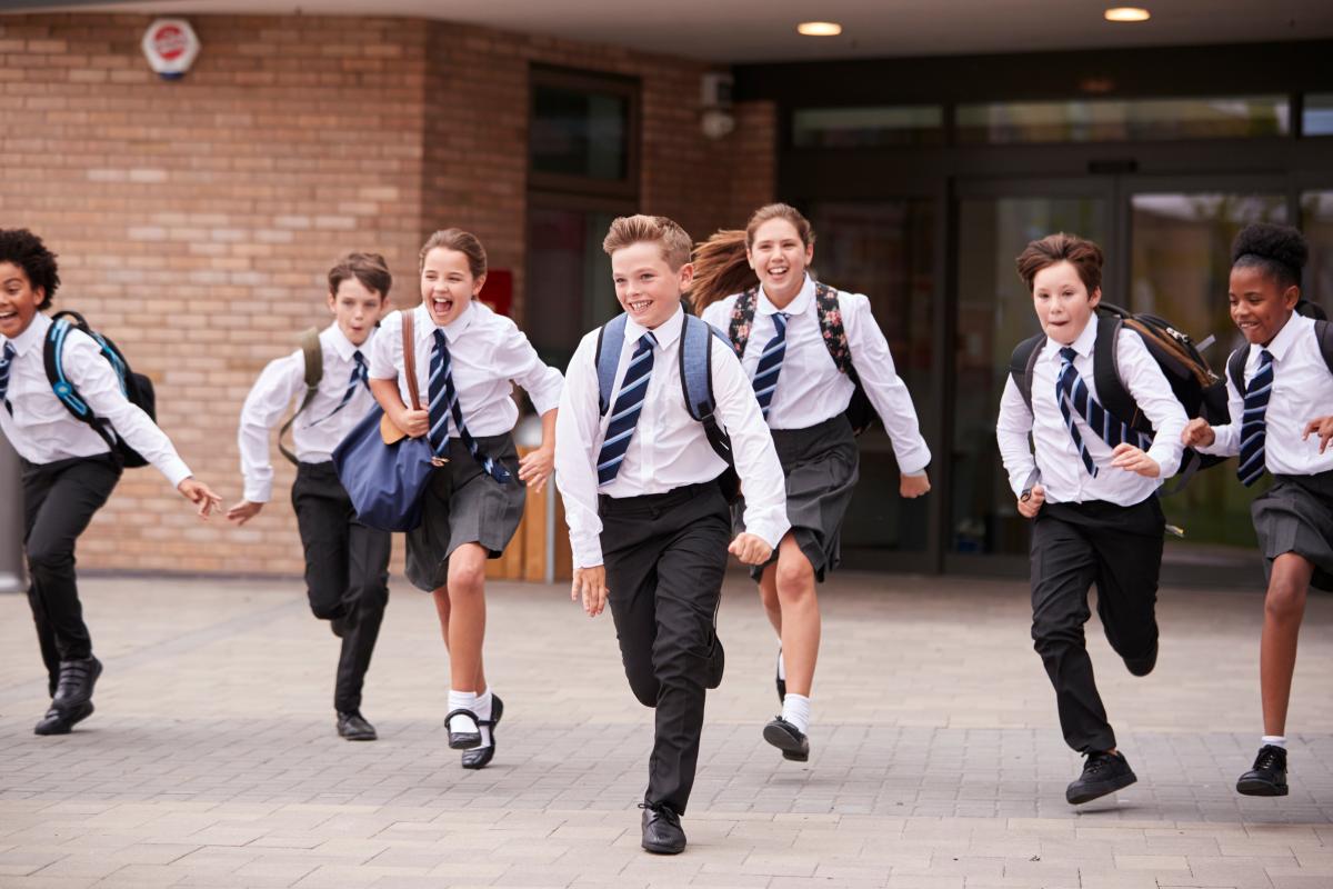 Young school children running while in their school uniforms. 