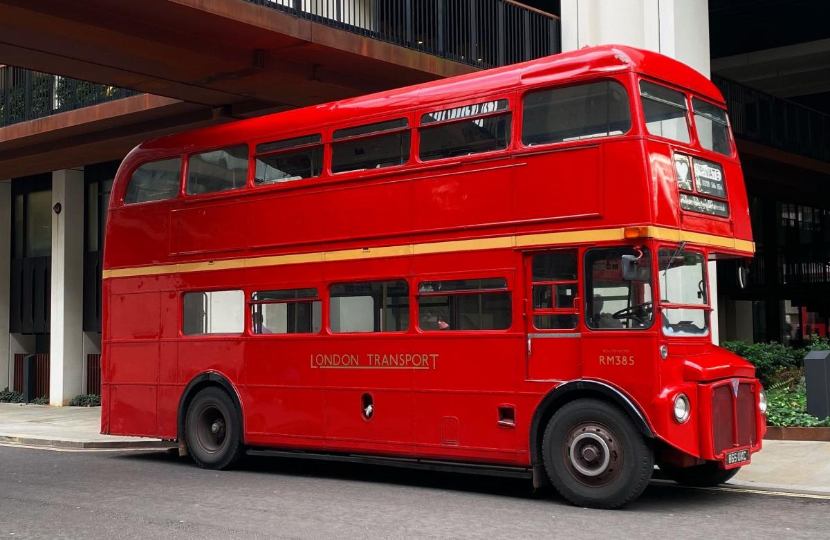 red double decker bus driving under a bridge