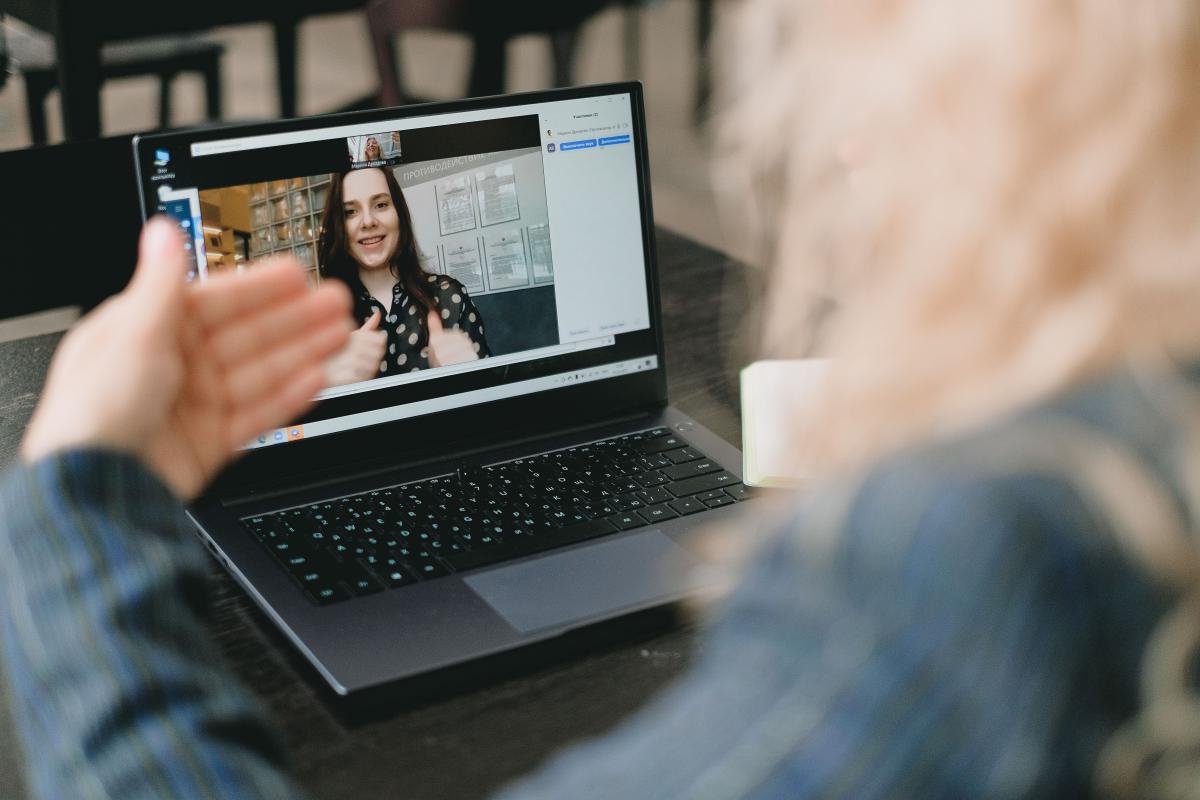 person looking at the screen of a laptop in front of them with a person on the screen smiling