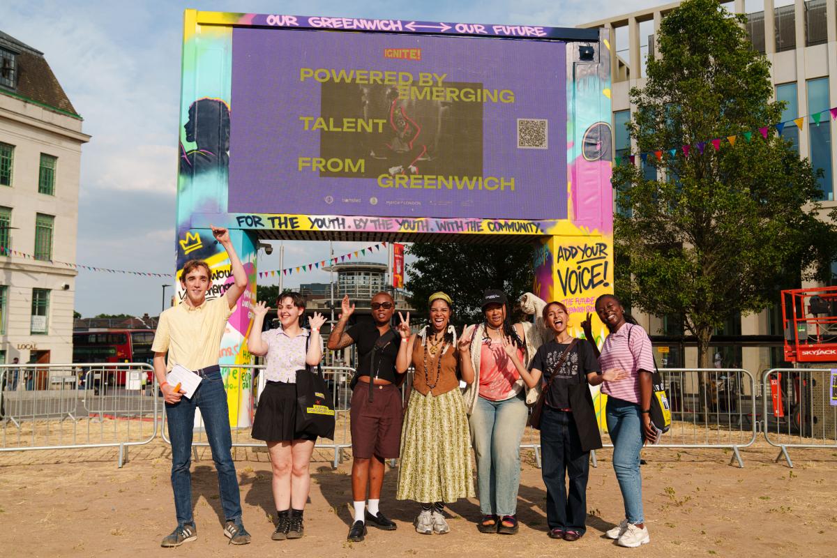 A group of young people in front of a colourful big screen that reads 'powered by emerging talent'