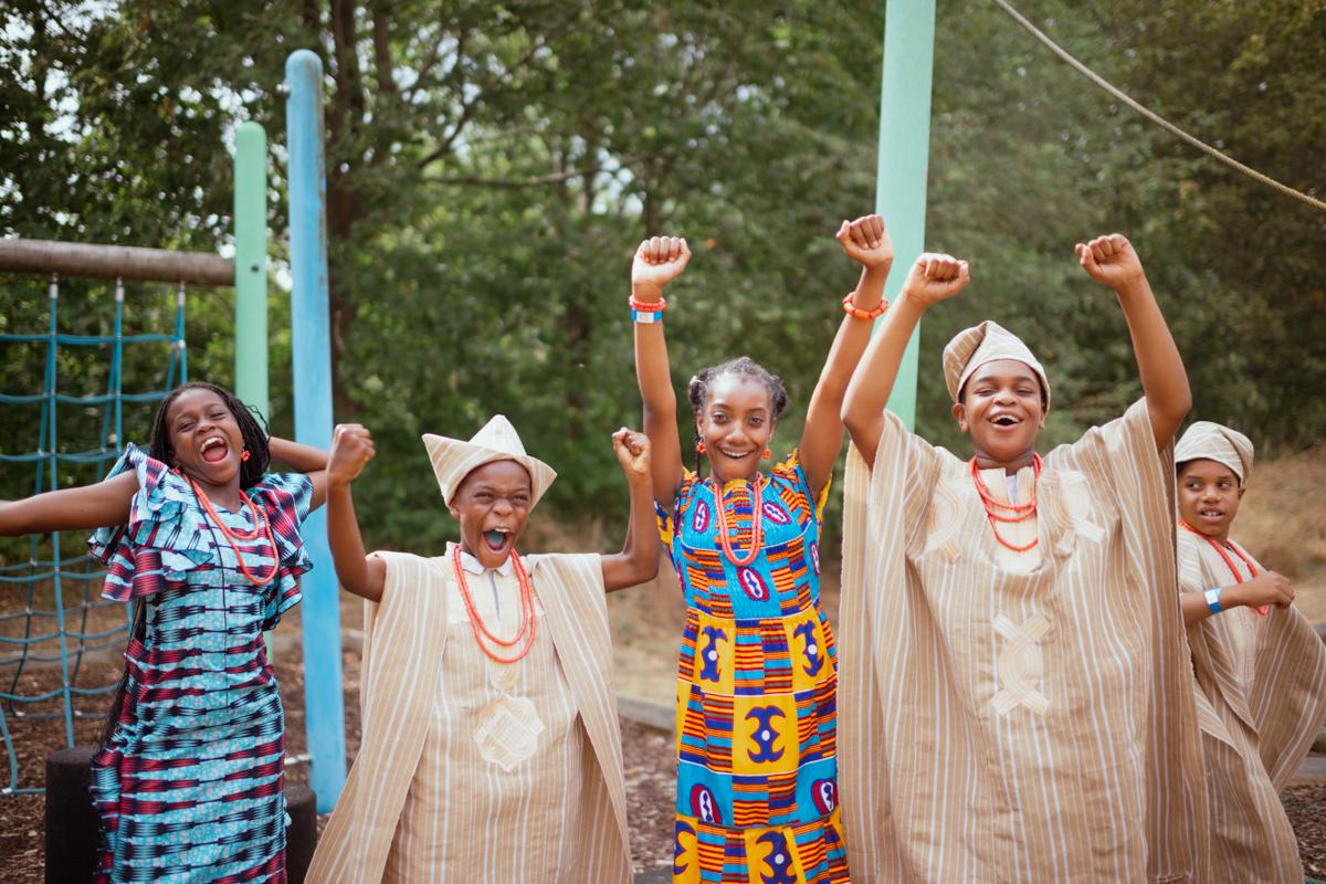 Five children smiling and cheering at an outdoor playground