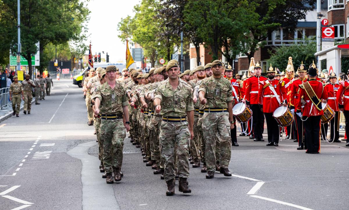 Uniformed soldiers and a marching band march down Wellington Street
