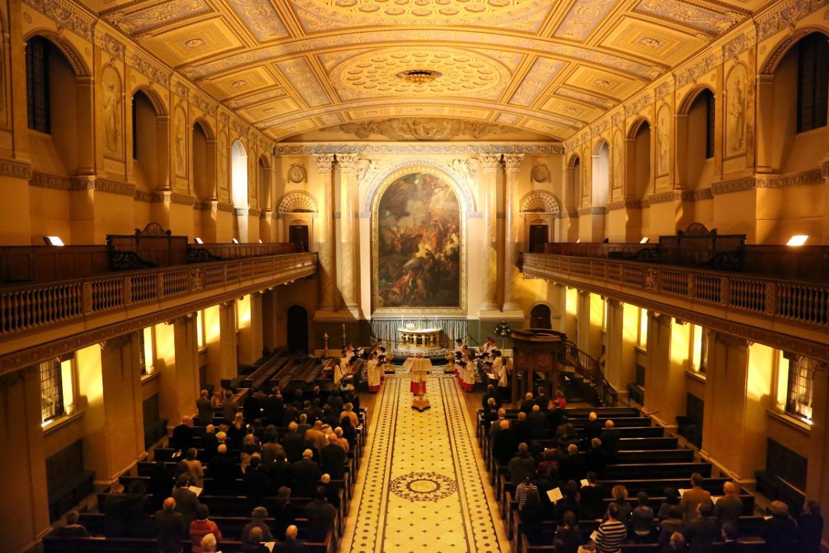 Inside a large church, with people sat either side of the aisle