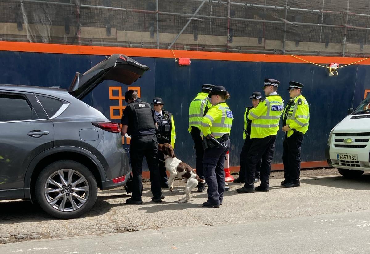 Police officers and a sniffer dog searching a car boot.
