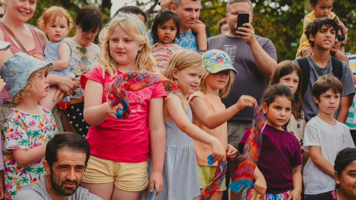 Group of children and adults standing together, waving hankerchiefs