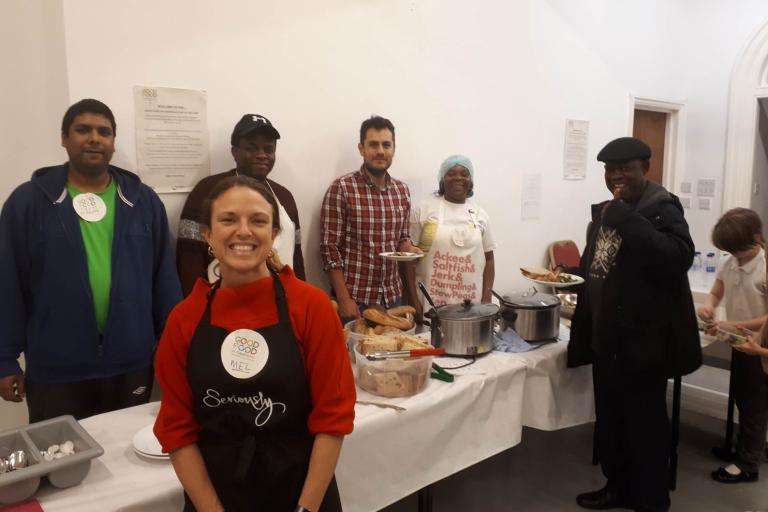 Good Food in Greenwich Community Kitchen - the image shows people putting themselves plates while smiling to camera, with staff also smiling at the camera