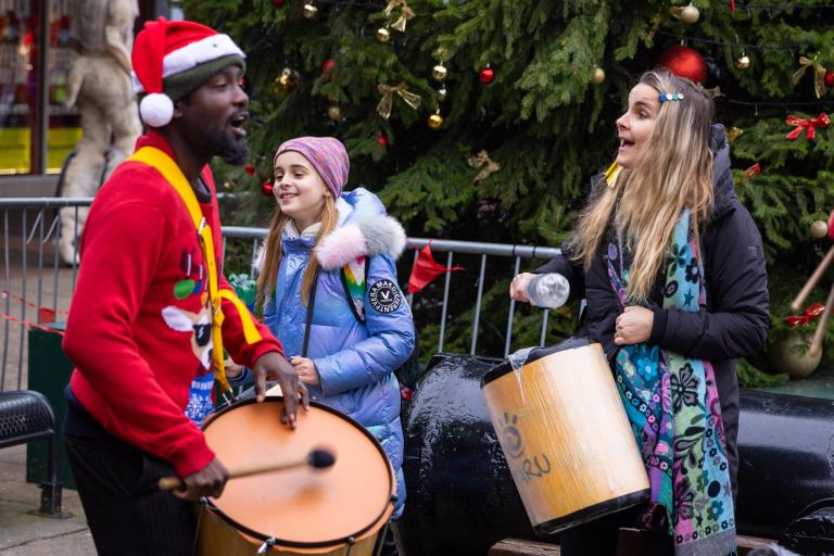 Three people playing drums in festive clothing
