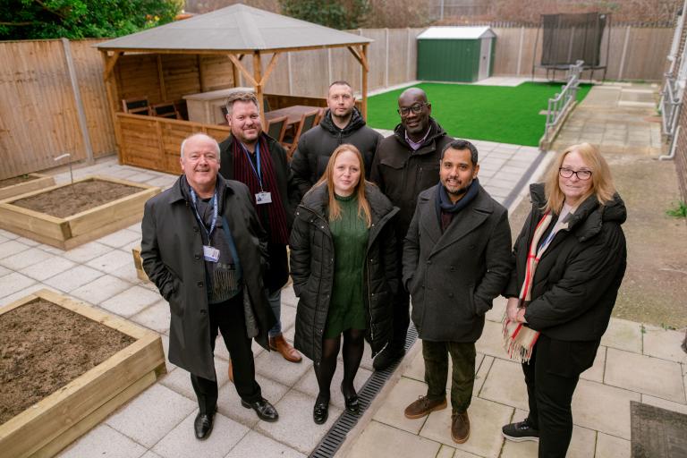 Photo showing Cabinet Member for Planning, Estate Renewal and Development Cllr Majid Rahman with care home staff and representatives from contractors Elkins Construction, Blakeney Leigh and Durkan Homes in the renovated garden at the children's care home.