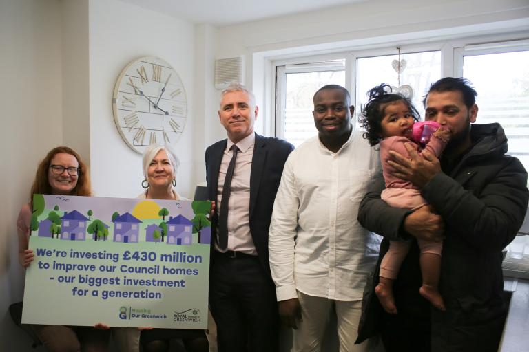 Council leader and Cllrs Taggart-Ryan and Cllr Slattery holding a sign that reads: 'We're investing £430 to improve our council homes - our biggest investment for a generation' with Andre Culleton standing in a newly renovated kitchen with a resident and his young child