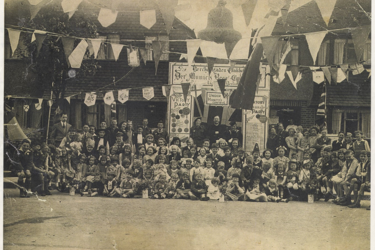 A group of people in front of a row of houses at a street party in 1945