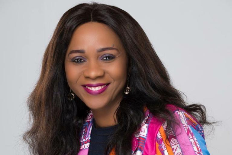 Publicity shot of Nadine Hagen. She is smiling and wearing a multicoloured top