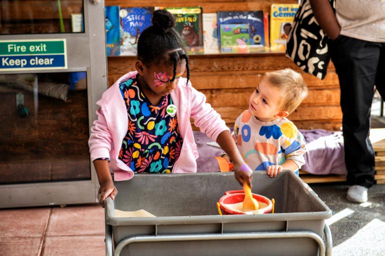 Two children playing with a sand pit.