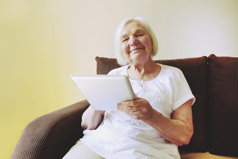 Image showing a resident using her new tablet to help her manage her own care.