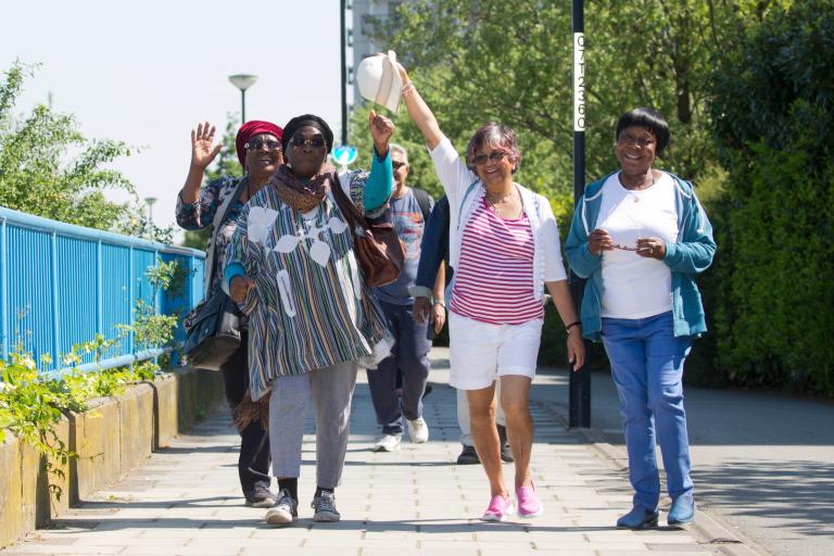 Group of people smiling and walking on the Thames Path