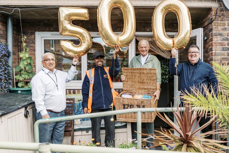 a group of people standing in a garden holding balloons that read 5-0-0