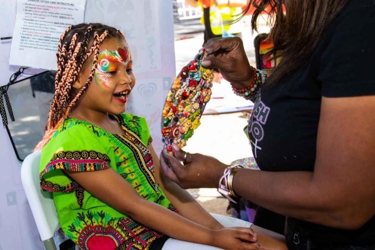 A little girl getting her face painted 