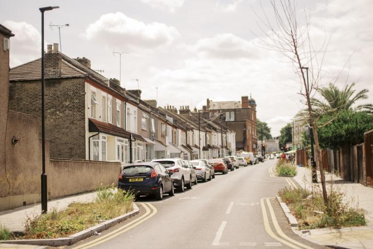 A street with green grass in the foreground and parked cars in the distance