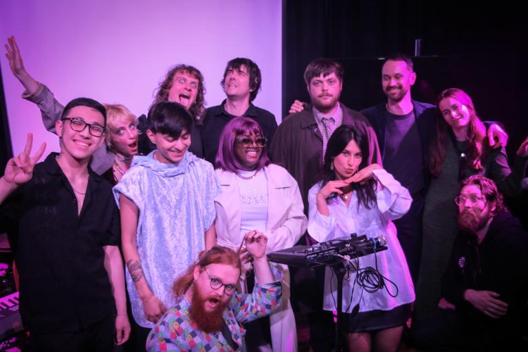 A group of people standing on a stage with a plain white backdrop
