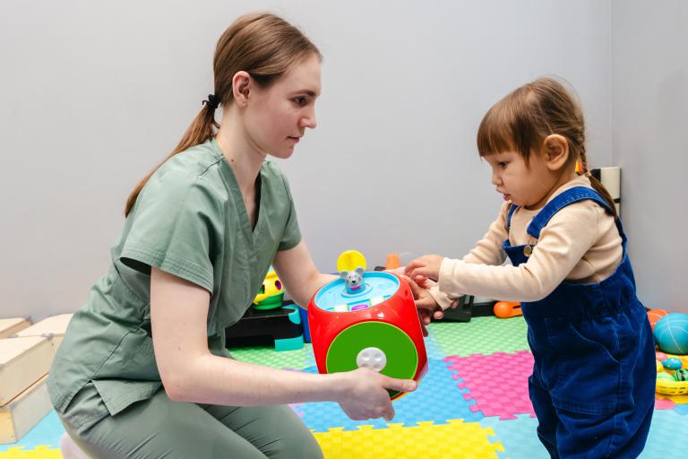 A woman holding up an educational toy to a young child.