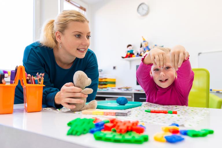 A woman holding a toy while a young girl shows off her painted nails at the camera.