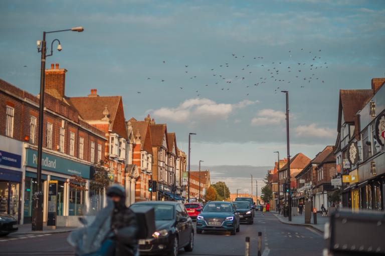 Landscape shot of Eltham high street with cars and motorbikes driving in the road