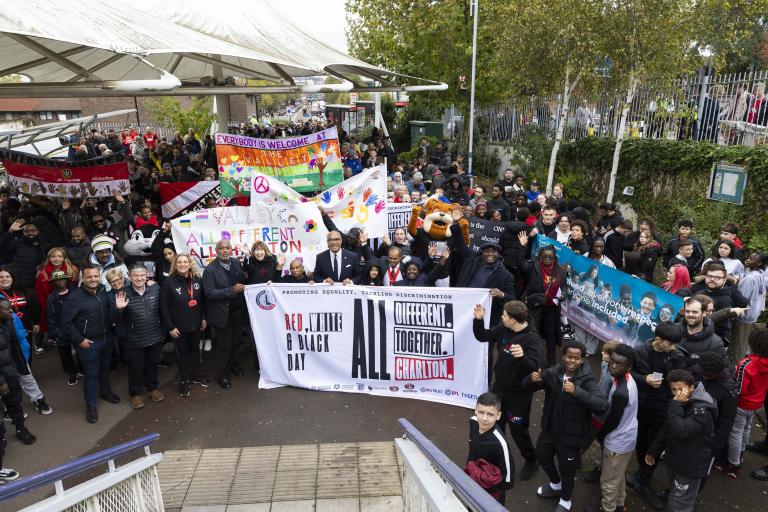 A crowd of people holding up signs promoting equality and anti-discrimination in football