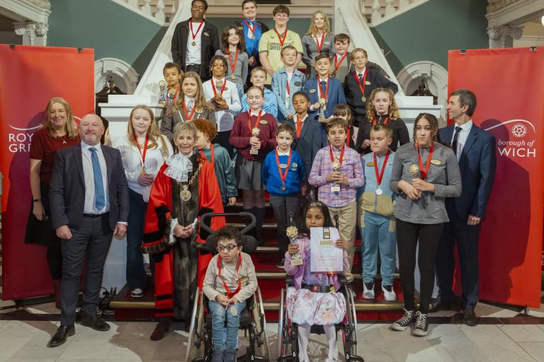 A group of students and dignitaries stand at the stairs in Woolwich Town Hall