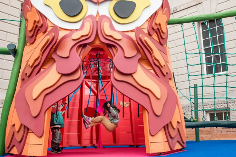 A child swinging on ropes in an owl-shaped wooden construct.