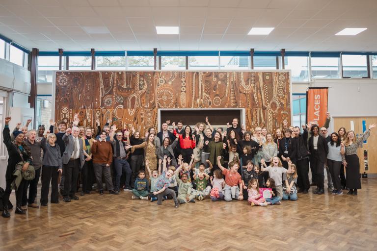 A group of residents, councillors, school pupils and heritage professionals celebrate in front of the restored Brooklands Mural by William Mitchell