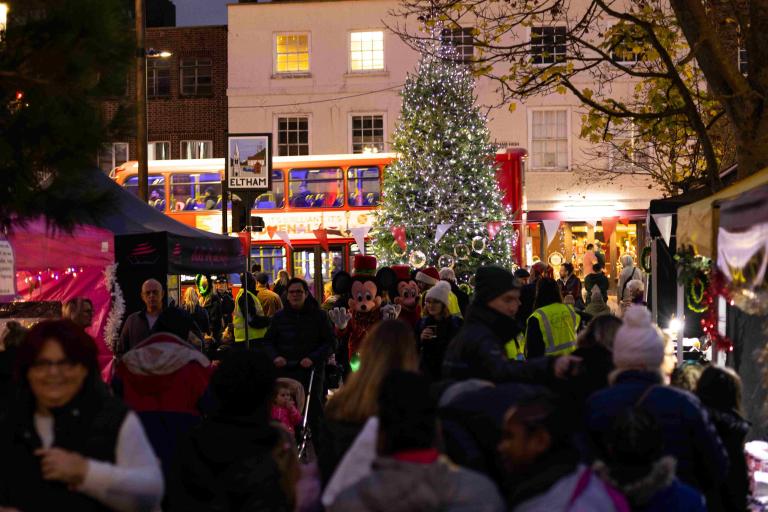 Christmas market huts lit up in the evening with a crowd of shoppers
