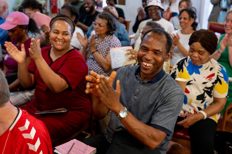 A room of seated people clapping.