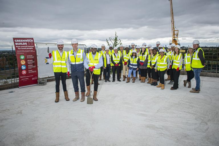 Deputy Mayor of London Tom Copley, Leader of the Royal Borough of Greenwich Cllr Anthony Okereke pose on the top floor of the concrete structure of a new council home development alongside other councillors and contractors