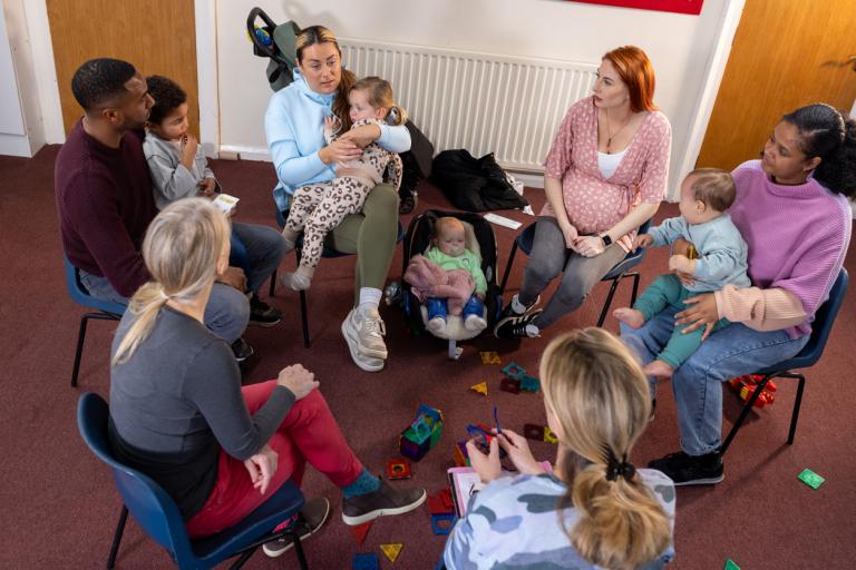 A circle of parents with their babies or soon to be parents. 