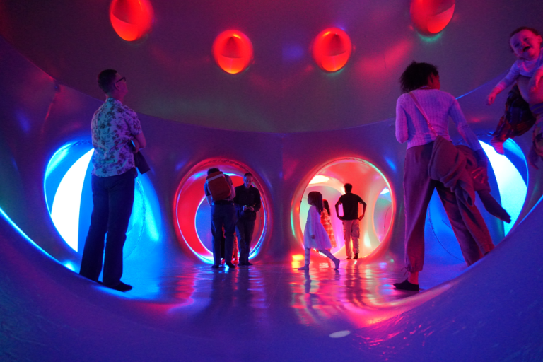 People exploring a colourful room filled with lights