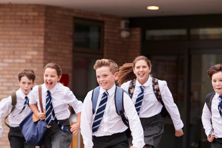Secondary school pupils in uniform running across playground