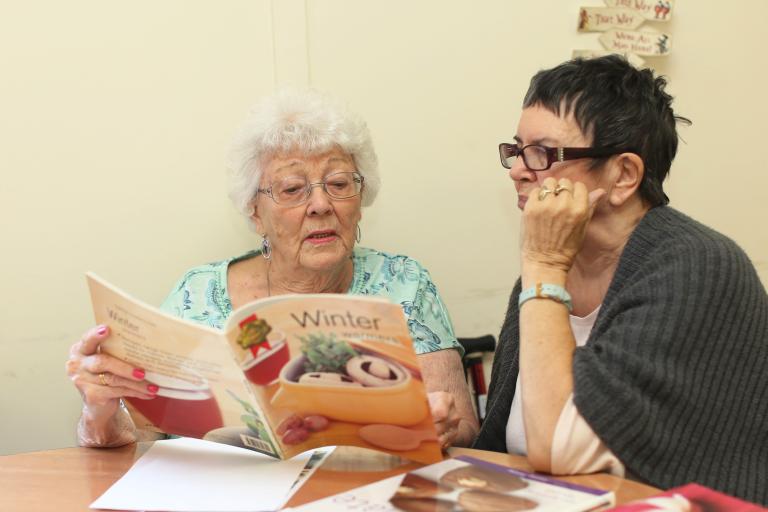 Two women reading a book together.