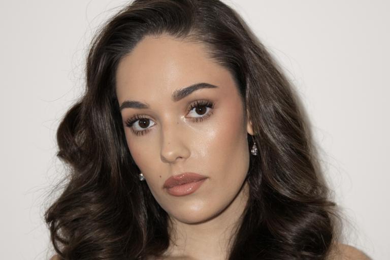 A woman with long brown hair looks to camera