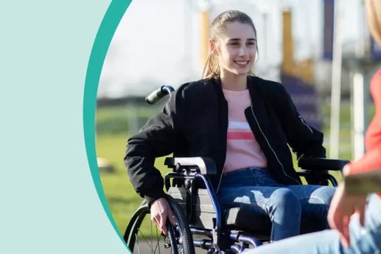 Young person in a wheelchair talking to another young person on a bench