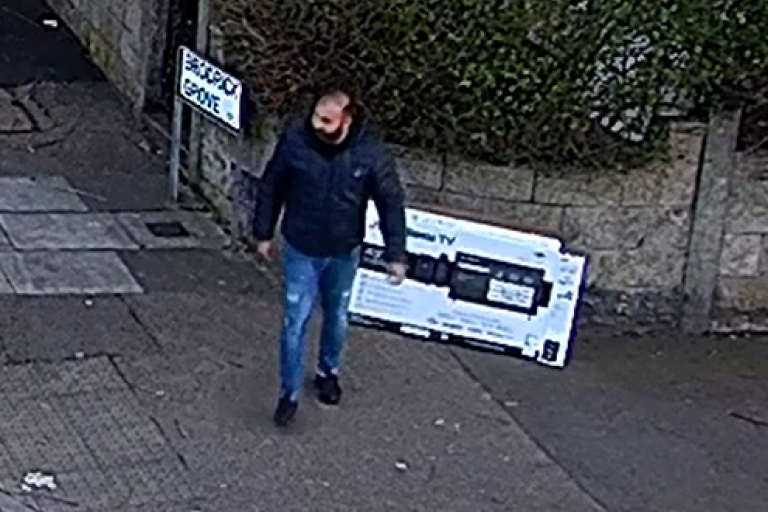 An image of a man drumping an empty TV package box on the side of the pavement and walking off