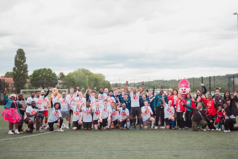 Group of people including two football squads celebrating in group shot