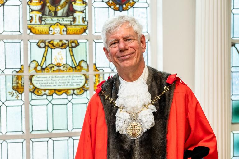 Councillor David Gardner smiling stood in front of a stained glass window
