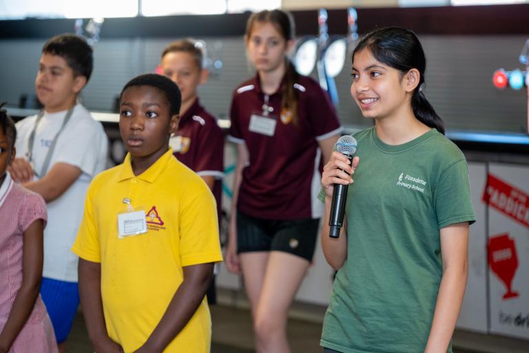 Students take part in warm up activity introducing themselves and sharing experience. Here one student holds a mic while smiling