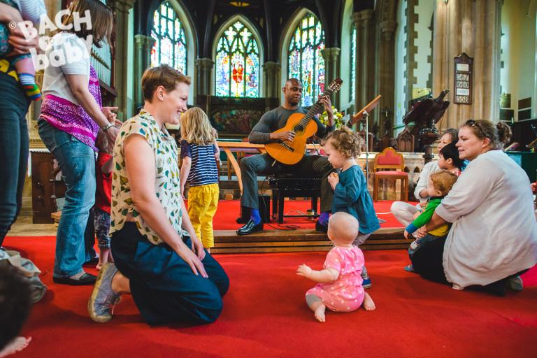 A guitarist with an audience of parents, babies and toddlers