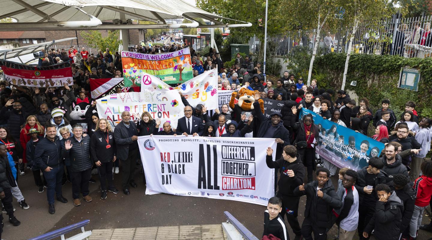 A crowd of people holding up signs promoting equality and anti-discrimination in football