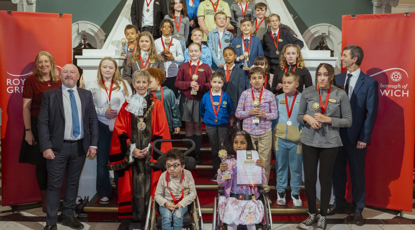 A group of students and dignitaries stand at the stairs in Woolwich Town Hall