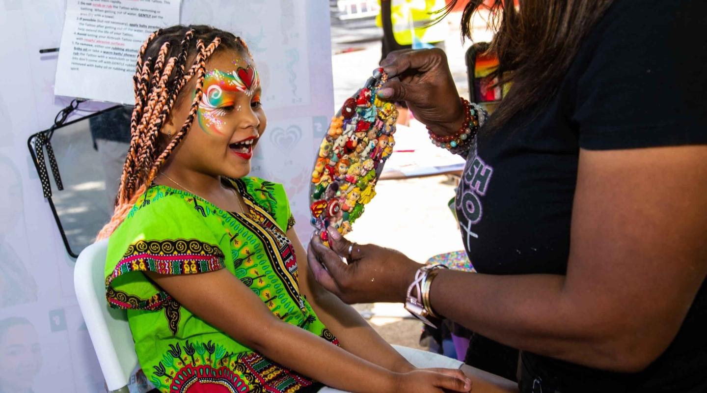 A little girl getting her face painted 